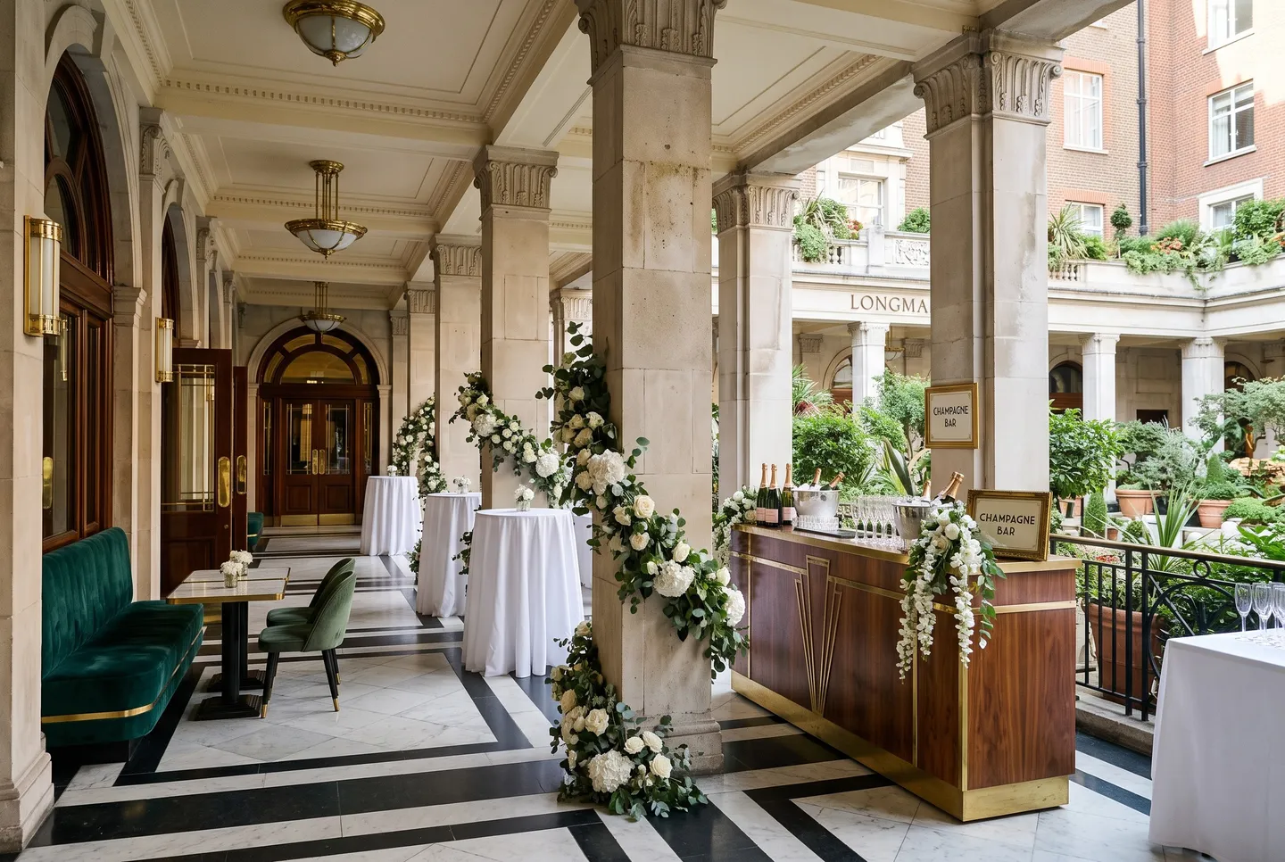 The stone Colonnade at Longman Hotel set for drinks, with a champagne bar and white flowers on the columns