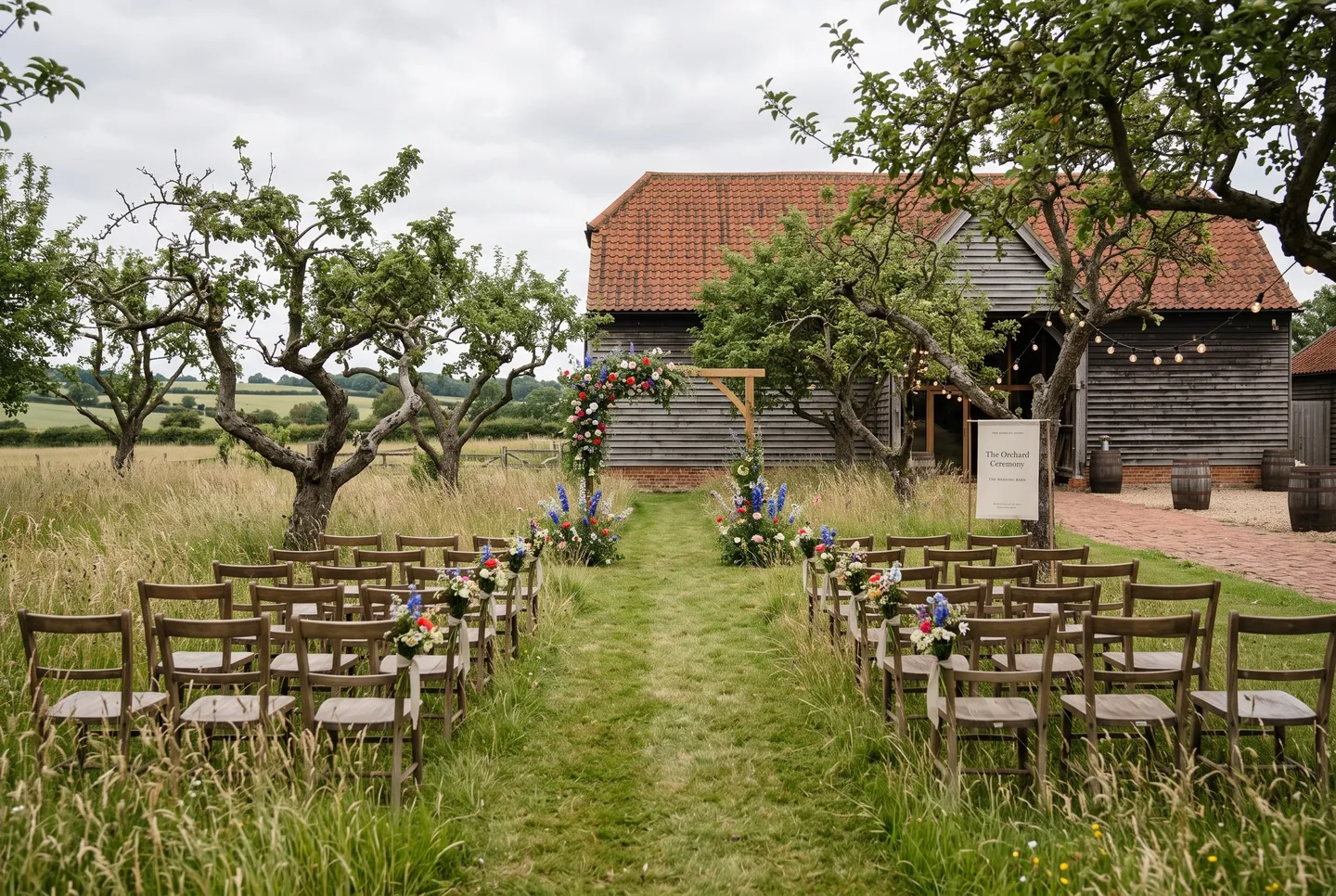 The Orchard at The Wedding Barn set for a ceremony, with an aisle mown through the long grass to a wildflower arch